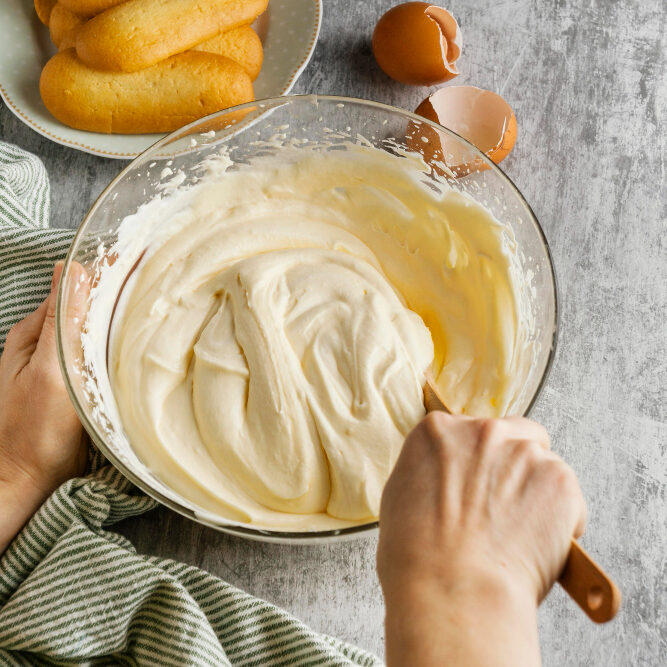 Cream cheese, sugar, and vanilla extract being mixed together in a bowl