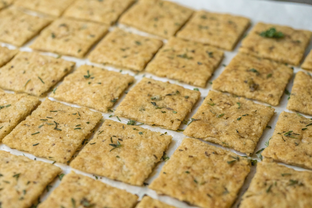 ultra-close-up view of crackers resting on a wire rack post-bake. Their curled edges and toasted tops glisten under natural lighting, inviting that first crunchy bite.